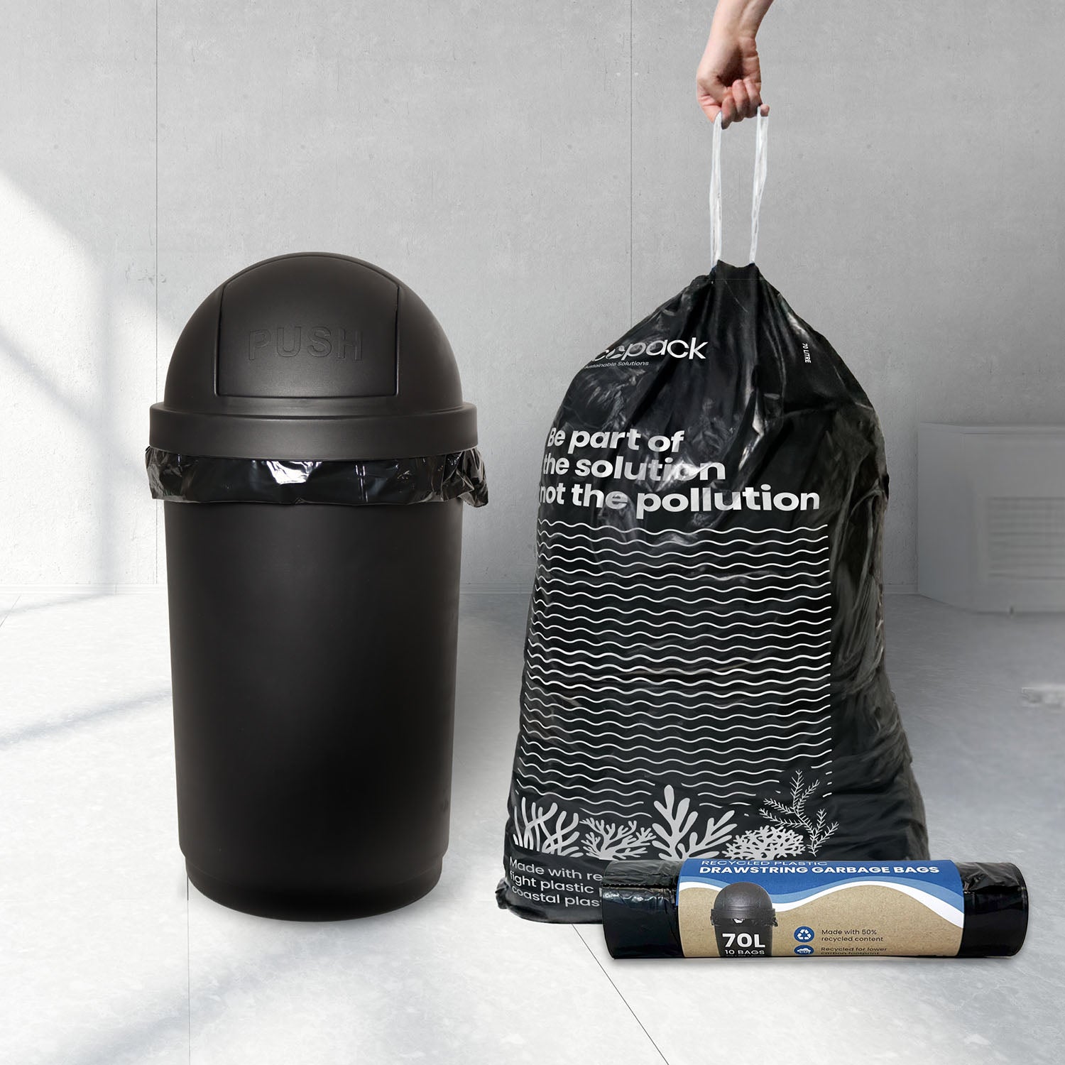 Black trash bin with a drawstring garbage bag and packaging on a light gray floor.